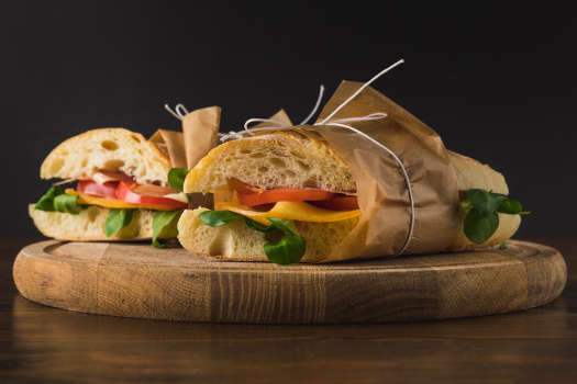 Panini wrapped in brown paper on cutting board